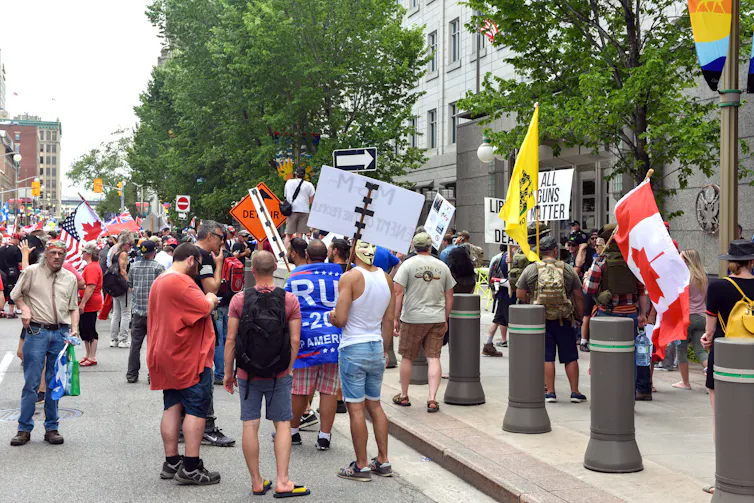People gather holding upside down Canada flags and pro Trump flags outside the U.S. embassy in Ottawa.