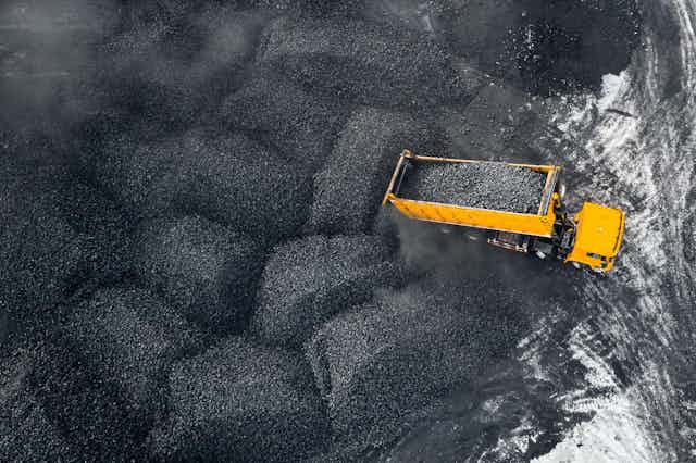 A yellow truck picks up coal from an open pit mine.