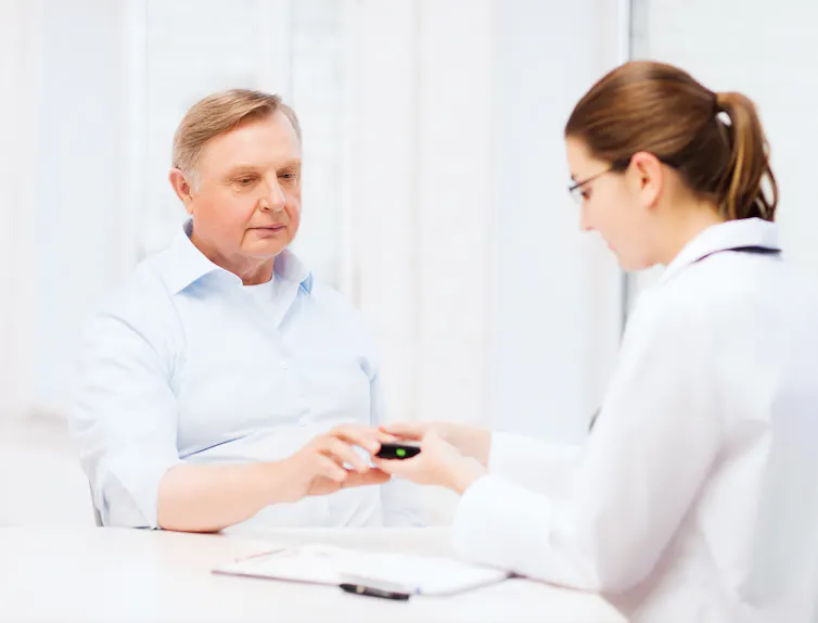 Female doctor measuring an elderly man's blood sugar levels.
