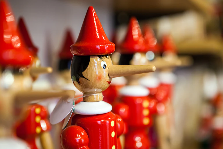 A row of wooden toy figures of Pinocchio.