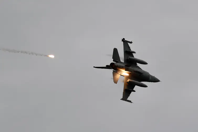 An airborne fighter jet fires a missile.
