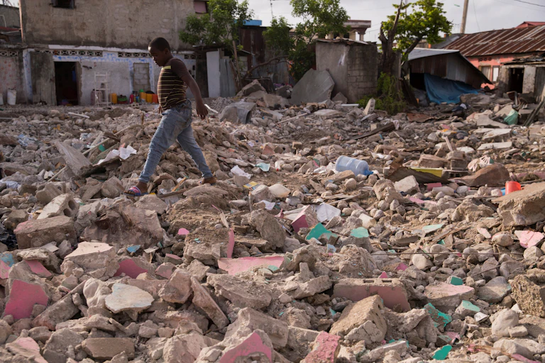 A boy walks through rubble in Haiti.
