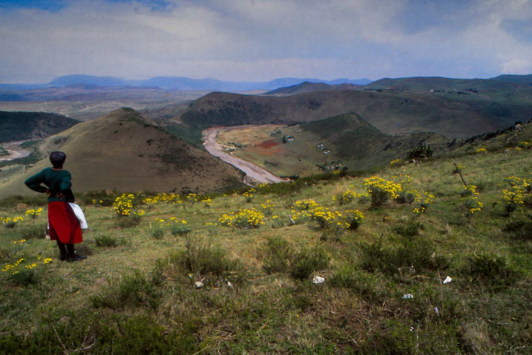 Woman stands on a hillside overlooking a rural valley