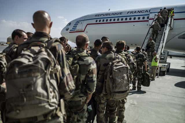Soldats en treillis montent dans un avion de ligne siglé République Française