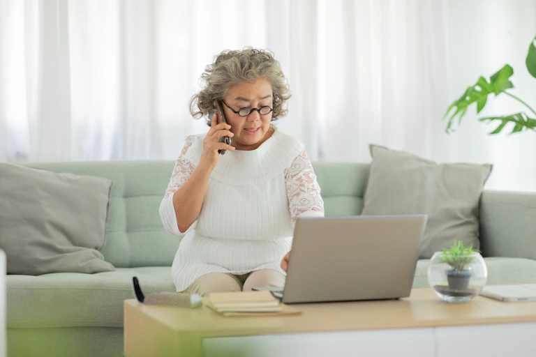 Woman on cellphone looking at laptop
