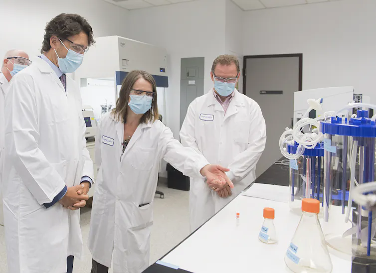 Justin Trudeau is surrounded by scientists, in a lab
