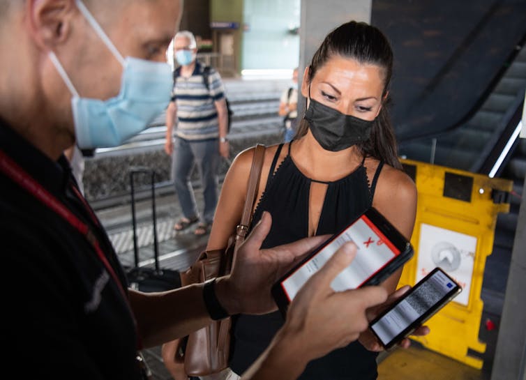 Passenger showing their COVID-19 vaccination green pass at a railway station, Rome, Italy