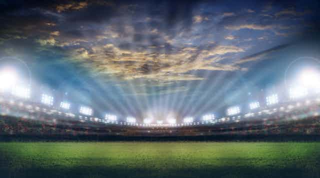 Brightly lit stadium under dramatic sky.
