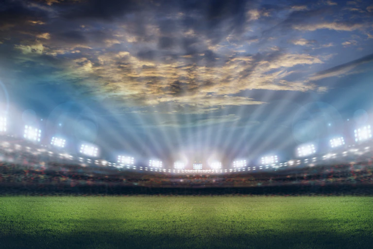 Brightly lit stadium under dramatic sky.