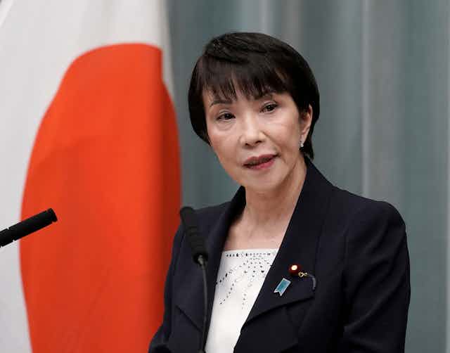 Japanese prime ministerial hopeful Takaichi Sanae poses in front of the naitonal flag.
