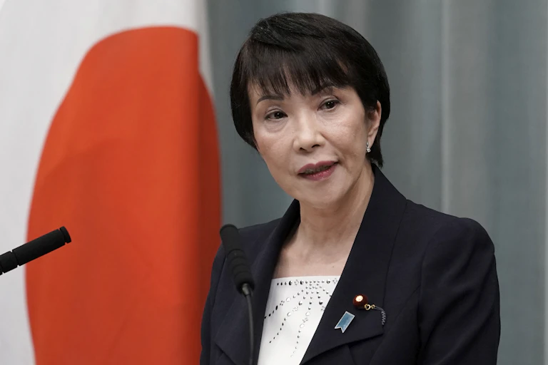 Japanese prime ministerial hopeful Takaichi Sanae poses in front of the naitonal flag.
