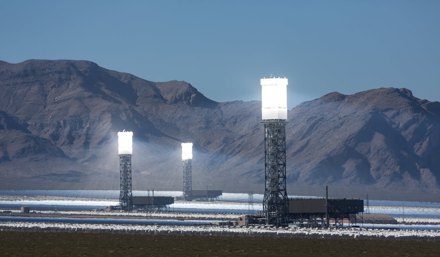 Three glowing solar towers in the desert.