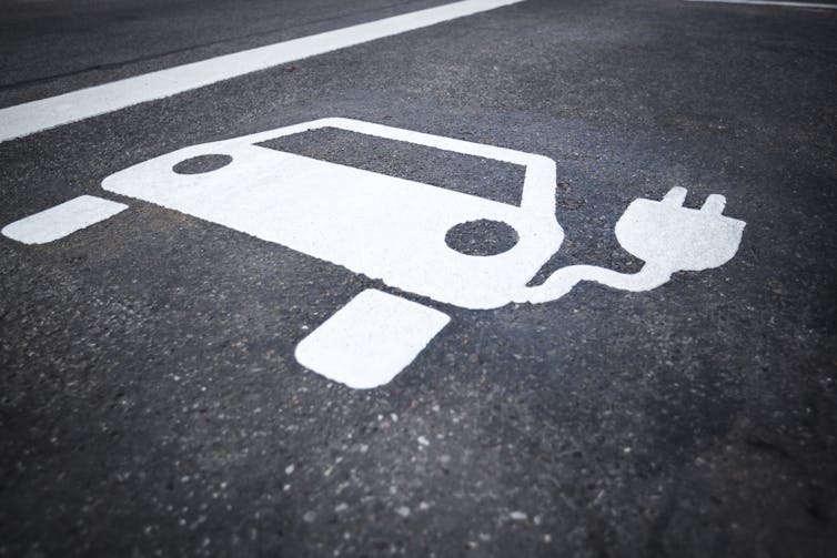 A painted electric vehicle symbol on asphalt