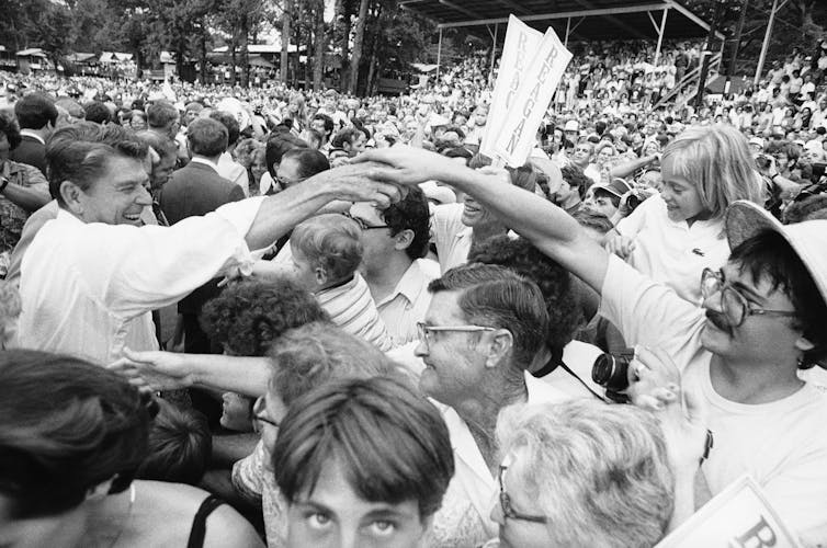 A man reaches out to a crowd of smiling people