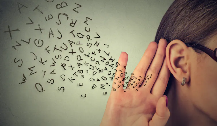 A flutter of letters travels towards a woman's ear.