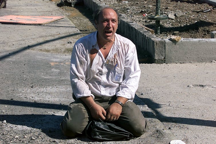 On 9/11, shortly after the terrorist attack in New York City, a distraught survivor sits outside the World Trade Center.