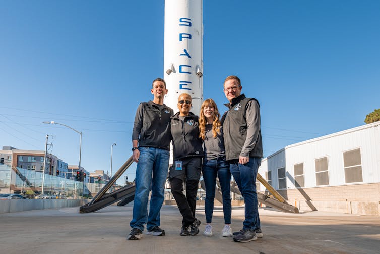 Four people standing in front of a rocket.