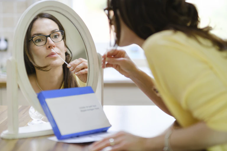 A woman performing a COVID-19 self-test at home.
