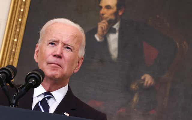 President Joe Biden addresses America in front of a portrait of Abraham Lincoln.
