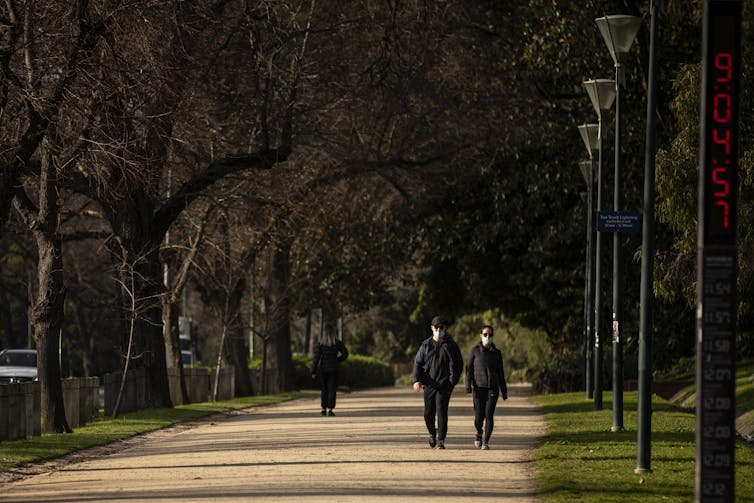 couple walking on track with masks on