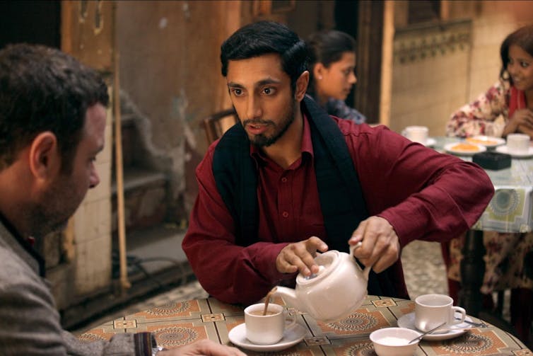 Two men sit at table drinking tea.