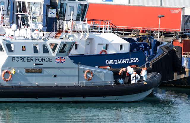 A Border Force boat in a Dover port with several people in lifejackets on board