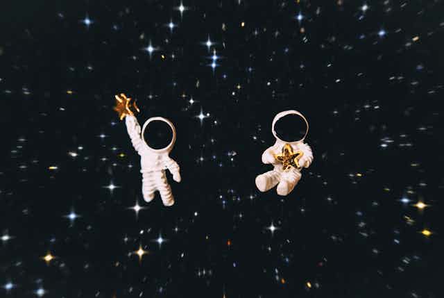 two astronaut figurines with a star background