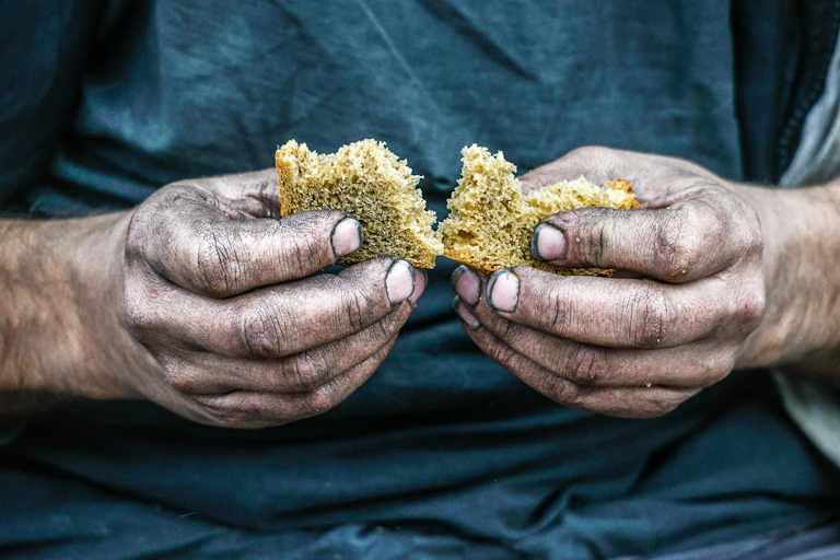 Two hands breaking a piece of bread
