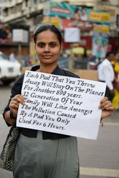 A woman in India holds a placard that reads 'Each pad that you throw away will stay on the planet for another 800 years. 12 Generations of your family will live amongst the pollution caused by a pad you only used for six hours.'