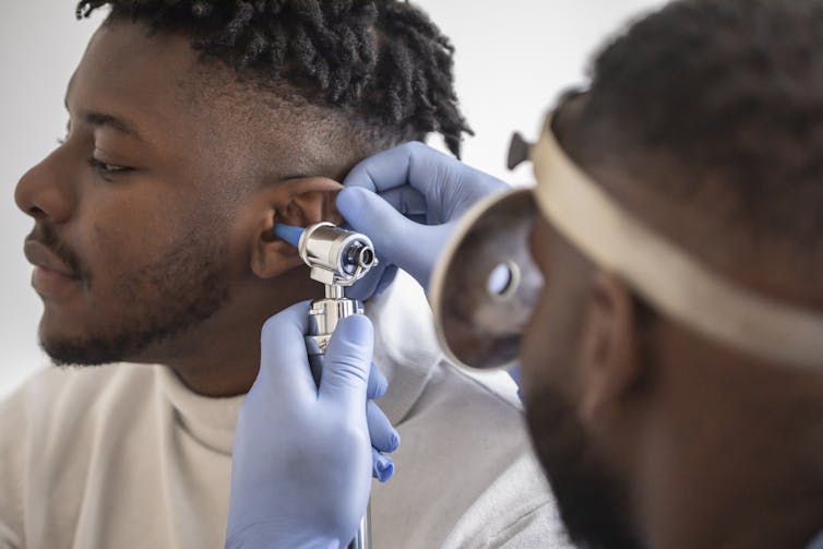 Health provider using otoscope to examine a patient's ear.