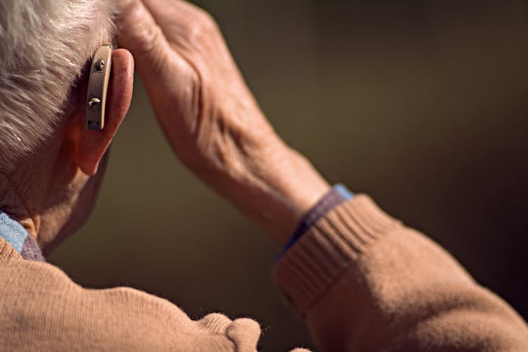 Older adult wearing hearing aid.