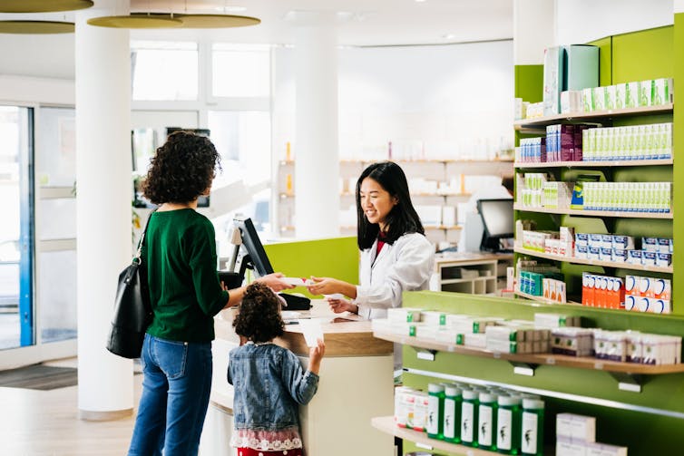 Adult and young child talking to pharmacist at the counter.