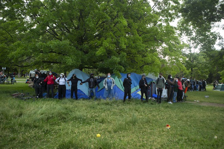 Advocates and supporters link arms to protect a structure during an eviction process at a homeless encampment