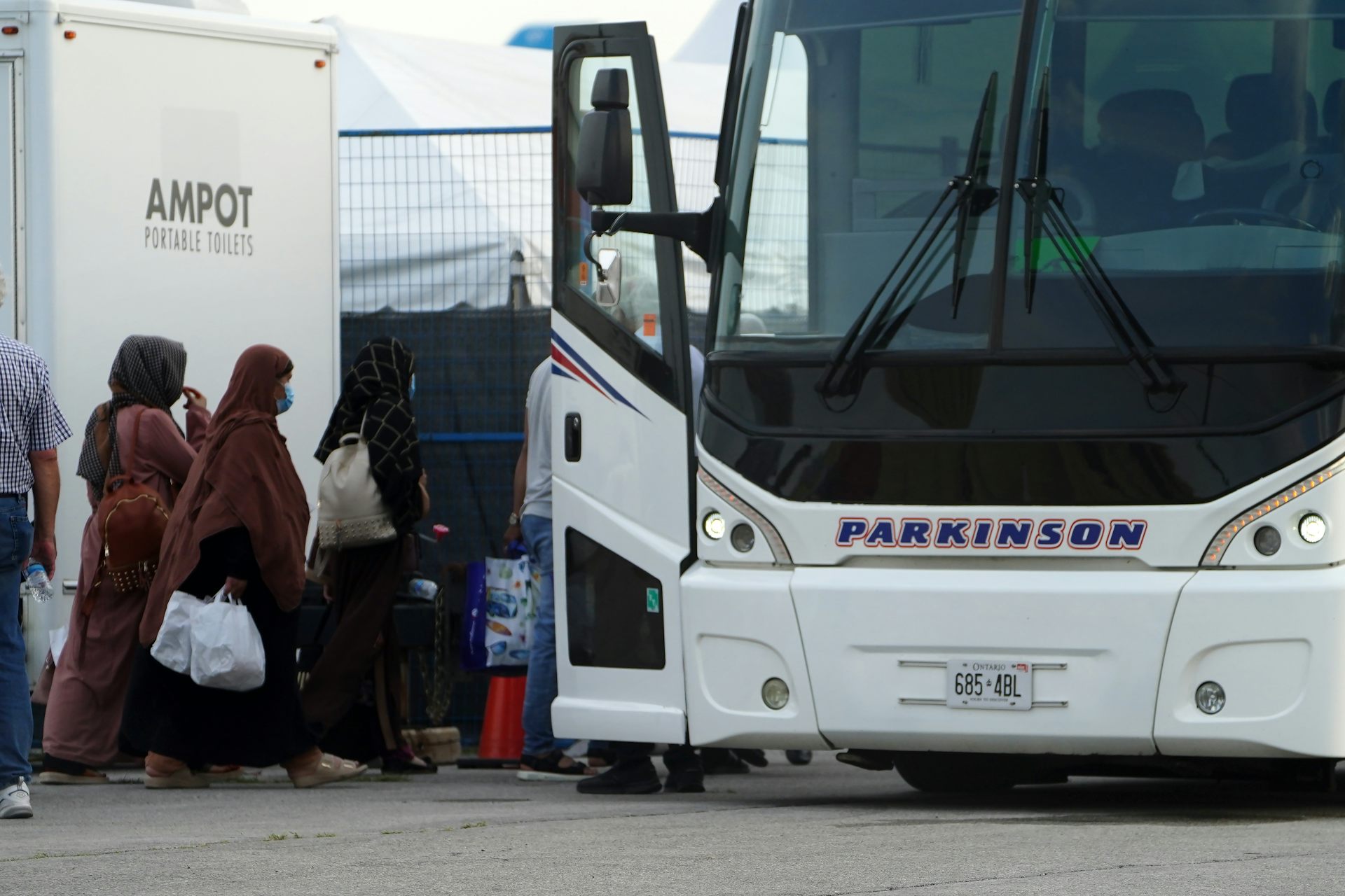 A group of people carrying bags are seen boarding a bus.