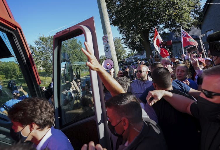 Trudeau getting on a bus in a crowd of people