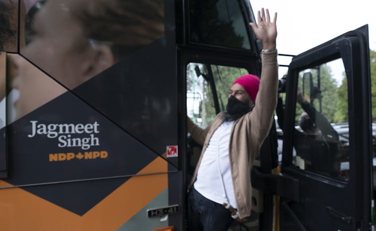 NDP Leader Jagmeet Singh waving in the doorway of his campaign bus.