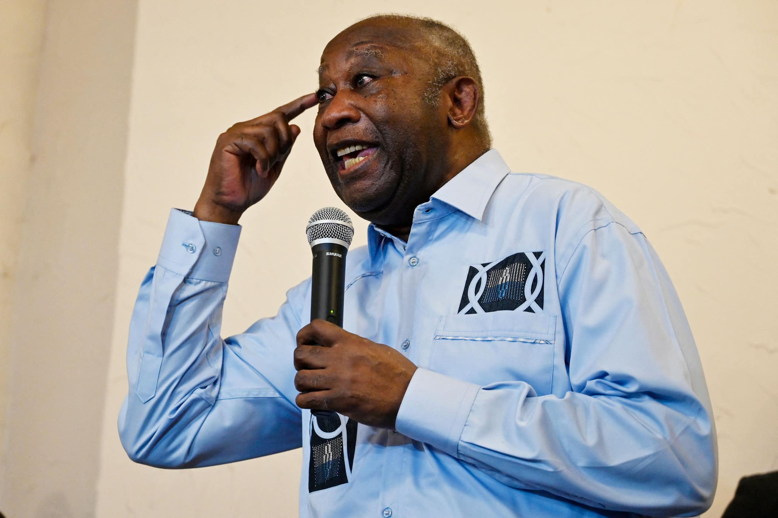 A man holding a microphone and gesticulating while speaking