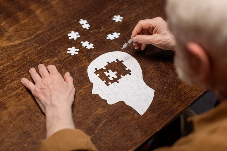Señor mayor haciendo un puzzle con forma de cabeza humana.