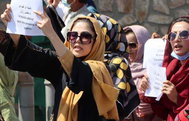 Afghan women protesting against the all-male government holding up messages in Arabic and English. at a demonstration in Kabul, September 3.