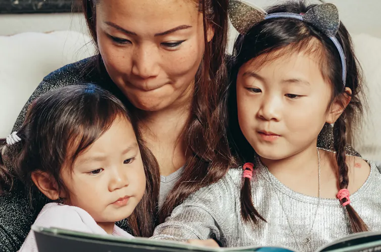 A mother reads to two daughters.