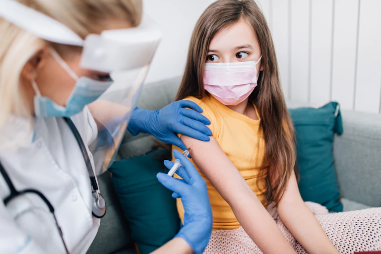 Una sanitaria vacuna a una niña.