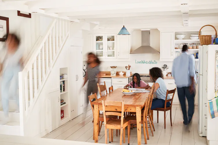 Family members sitting at a table while some pass by in a blur.