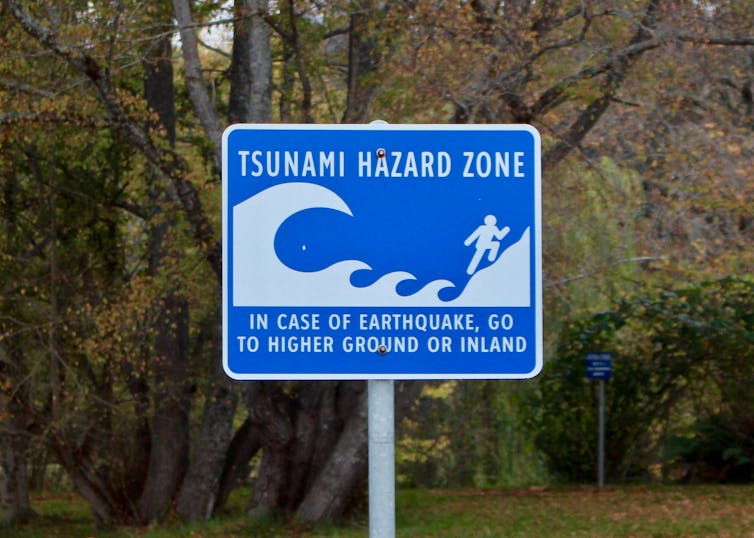 Sign reading TSUNAMI HAZARD ZONE IN CASE OF EARTHQUAKE GO TO HIGHER GROUND