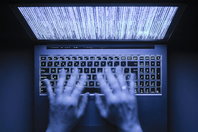 Two hands types quickly on a laptop's keyboard.