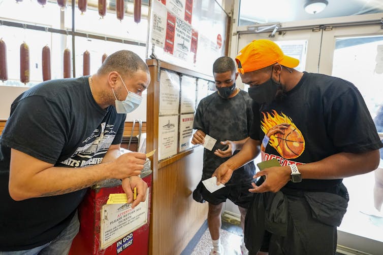 An employee of Katz's Deli in New York City looks down to inspect a customer's vaccination card