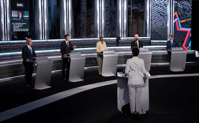 The federal party leaders standing at podiums during the French-language debate on Sept. 8, with moderator in foreground