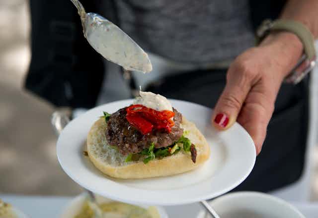 A person puts dressing on an insect burger  during a global Pestaurant event in Washington in 2014.