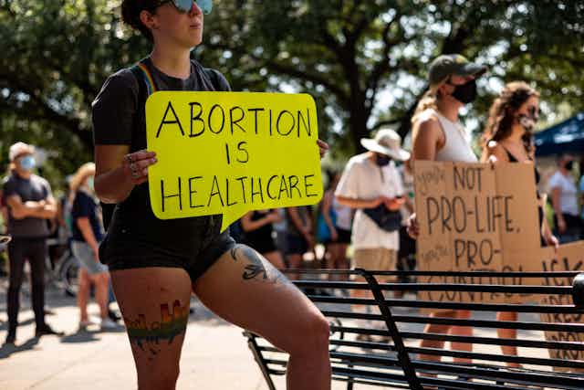 Person holding sign at protest reading "Abortion Is Healthcare"