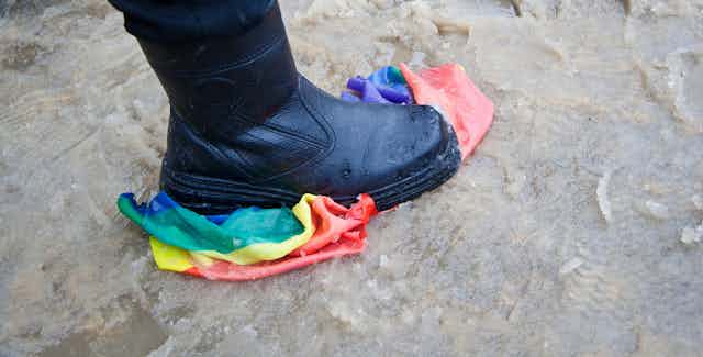 Una bota negra pisando una bandera arcoíris.