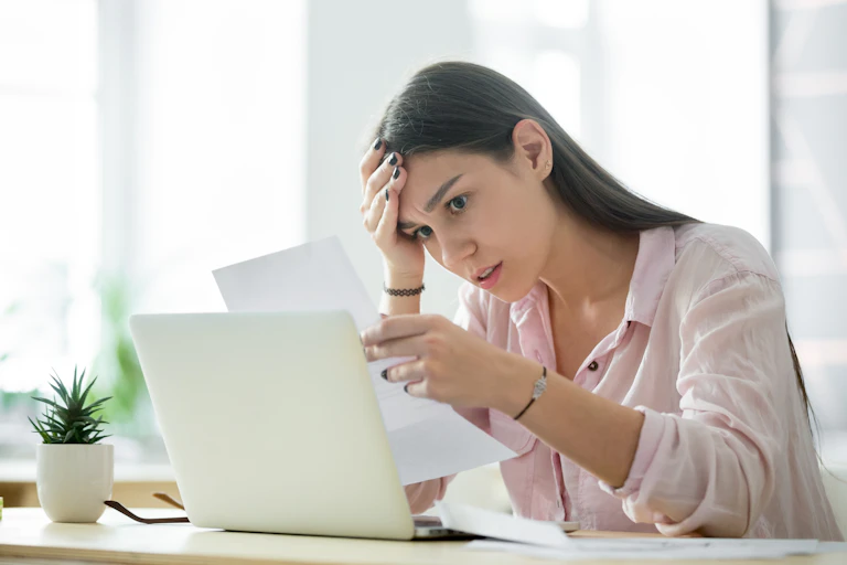 Women puts her hand to her head as she reads a troubling document